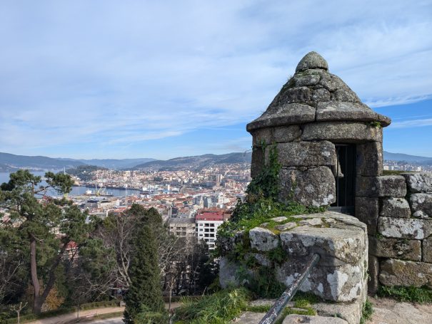 Stone lookout tower with city and coastline view in the background, located at Castelo do Castro in Vigo Spain.