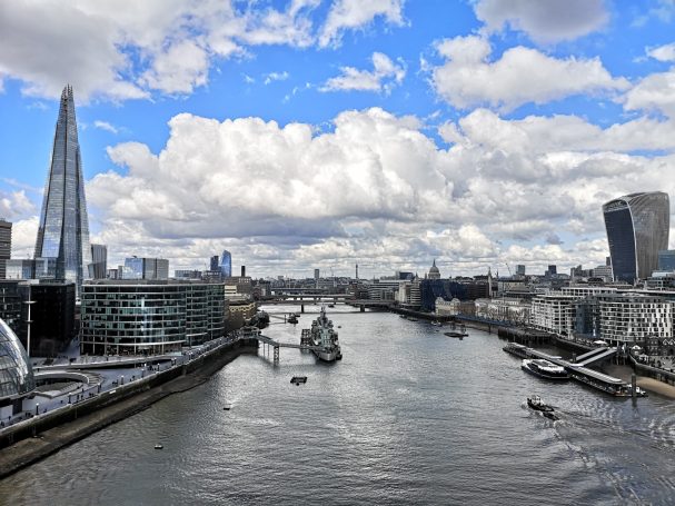 View of the River Thames with London skyscrapers and clouds in a blue sky.