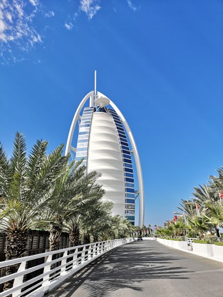 Burj Al Arab hotel with palm trees and bright blue sky in the background.
