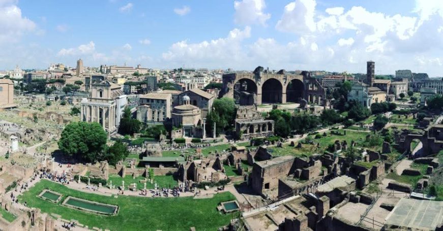 Panoramic view of the ancient Roman Forum under a clear blue sky.