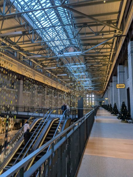 Modern interior featuring an escalator and large glass windows.
