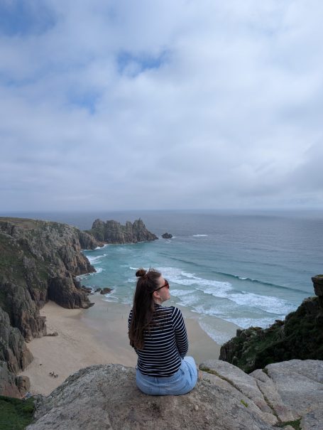 I&B's Founder posing on the cliffs of Cornwall in the UK with a cloudy sky and ocean in the background.