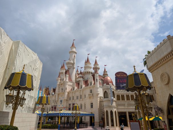 Fairytale castle surrounded by ornate lamps under a cloudy sky.