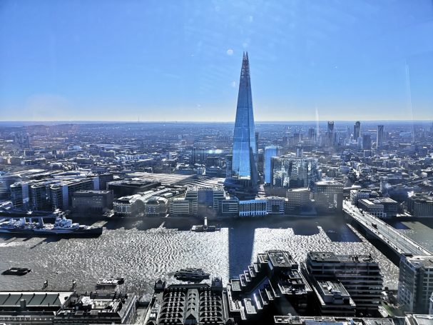 View of London with The Shard prominently rising above the skyline by the River Thames.